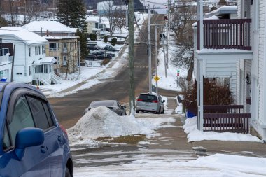 Kanada, Quebec, 19 Kasım 2025: Otomobilleri, evleri, kış kaldırımları, ağaçları olan karlı banliyö caddesi