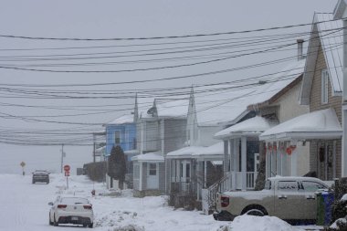 Kanada, Quebec, 30 Kasım 2025: Karlı mahalle evleri, elektrik hatları ve park halindeki araçlarla dolu