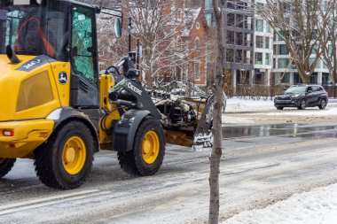 Kanada, Montreal, 25 Aralık 2025: Sarı araç kış mevsiminde karlı kentsel caddeyi temizledi.