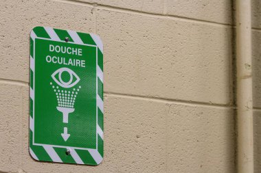 Kanada, Quebec, 03 Aralık 2025: Bej renkli endüstriyel tesis duvarında yeşil acil durum işareti