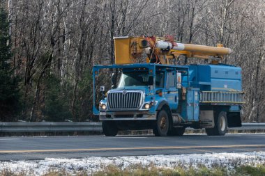 Kanada, Quebec, 08 Kasım 2025: Mavi kamu kamyonu kış başında karlı yol kenarındaki ormandan geçiyor