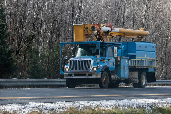 Kanada, Quebec, 08 Kasım 2025: Mavi kamu kamyonu kış başında karlı yol kenarındaki ormandan geçiyor