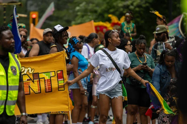 Kanada, Quebec, 05 Temmuz 2025: Genç kadın neşeli çeşitli kalabalıklarla çevrili canlı bir geçit törenine liderlik ediyor