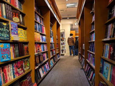 Kanada, Montreal, 22 Aralık 2025: Rahat kitapçı koridorlarında renkli kitap kuyruğu rafları