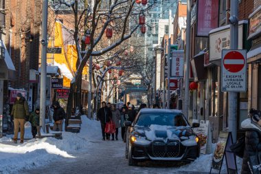 Kanada, Montreal, 24 Aralık 2025: Karlı, insanlı, arabalı, dekoratif fenerli kentsel kış sahnesi.