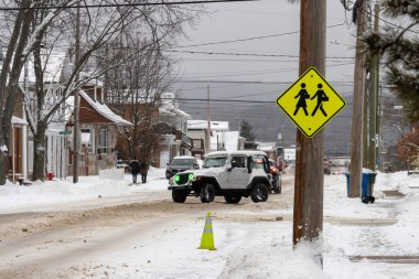 Kanada, Quebec, 10 Kasım 2025: Kar, sokak sahnesini jip, uyarı işareti, yayalar ve kış atmosferiyle kapladı