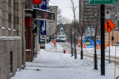 Kanada, Montreal, 25 Aralık 2025: Karlı şehir sokak manzarası, inşaat tabelaları, arka planda heykel.