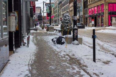 Kanada, Montreal, 25 Aralık 2025: Kış mevsiminde dükkanları ve yayaları olan karlı şehir caddesi