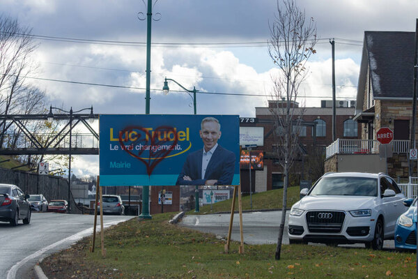 Canada, Quebec, 08 November 2025 : Political campaign sign with graffiti heart, city street with cars