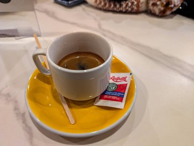 Kanada, Montreal, 25 Aralık 2025: Sarı çay tabağı, şeker paketi ve karıştırıcı üzerine Espresso bardağı.