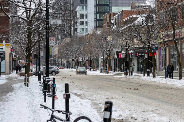 Kanada, Montreal, 25 Aralık 2025: Park halindeki bisikletli, yürüyen, binaları olan karlı şehir sokağı.