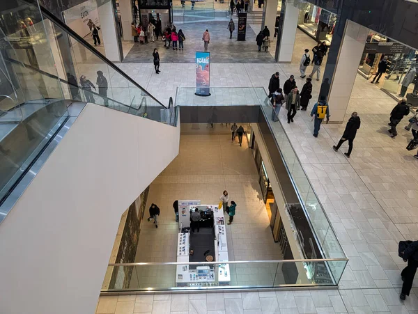Kanada, Montreal, 23 Aralık 2025: Alışveriş merkezinin içini yürüyen merdiven ve cam parmaklıklarla keşfeden müşteriler