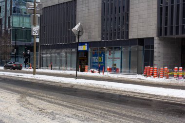 Kanada, Montreal, 25 Aralık 2025: Karlı kentsel sokak inşaat bariyerleri ve trafik işaretleri görünür