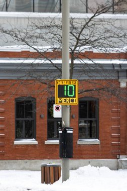 Kanada, Montreal, 24 Aralık 2025: Karlı kış sokak sahnesi hız işareti ve çıplak ağaçla.