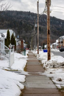 Kanada, Quebec, 27 Kasım 2025: Kar, telefon direkleri, arabalar ve evlerle kaplı banliyö kaldırımı