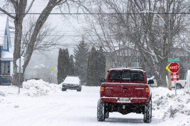 Kanada, Quebec, 30 Kasım 2025: Şiddetli kar yağışı sırasında kırmızı kamyonet karlı sokağa park edildi.