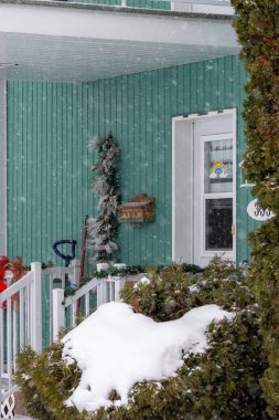 Kanada, Quebec, 30 Kasım 2025: Çalıları kaplayan kar, sıcacık bir kış verandası sahnesi, görünür dekorasyonlar
