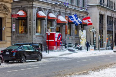 Kanada, Montreal, 24 Aralık 2025: Kentsel kış sahnesi, kar, bayraklar, mimari, park edilmiş arabalar, sokak.