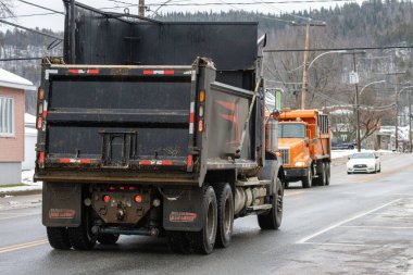 Kanada, Quebec, 27 Kasım 2025: Islak kış sabahı banliyö yolunda kırsal yolda giden çöp kamyonları