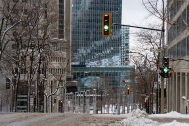 MONTREAL, CANADA, 24 Aralık 2025: Winter City Caddesi, karla kaplı yol, şehir mimarisi, trafik ışıkları, gökdelenler, çorak ağaçlar