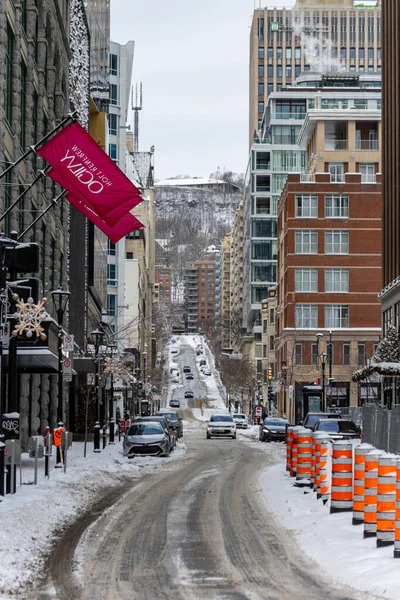 MONTREAL, CANADA, 25 Aralık 2025: Kış kentsel sokak sahnesi, karla kaplı şehir manzarası, modern mimari, trafik ve inşaat tabelaları, soğuk hava atmosferi, arka planda dağlar