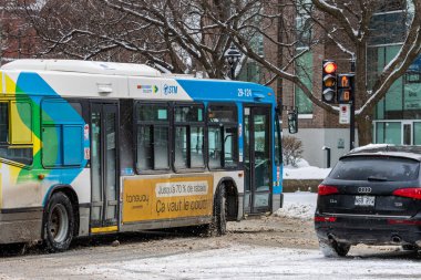 Kanada, Montreal, 25 Aralık 2025: Otobüs ve araba karlı kavşakta kırmızı ışıkta durdu