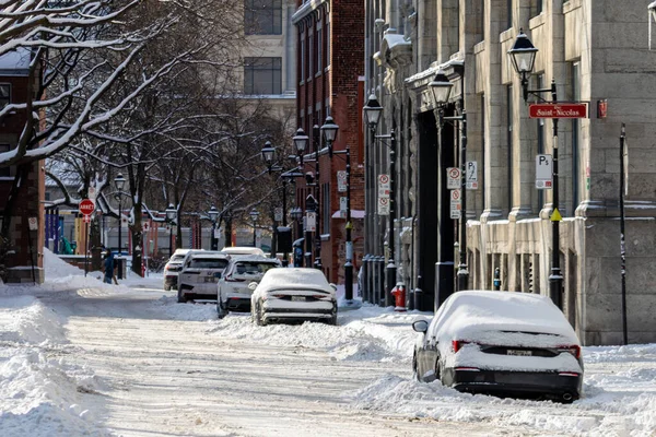 MONTREAL, CANADA, 24 Aralık 2025: Karlı şehir caddesi, park edilmiş arabalar, kış sahnesi, tarihi binalar, kentsel mimari, karla kaplı ağaçlar, gündüz atmosferi