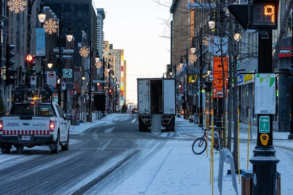 Kanada, Montreal, 22 Aralık 2025: Karlı şehir sokağı, kamyonlar ve bisikletler, kış sabahı ışıkları.