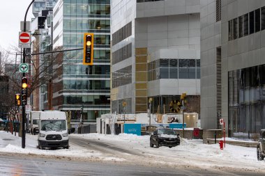Kanada, Montreal, 24 Aralık 2025: Trafik ışıkları ve modern binalarla karlı şehir kavşağı.