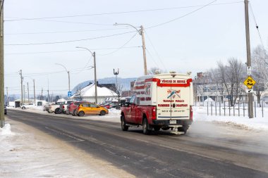 Kanada, 25 Ocak 2026: Karlı cadde, kırmızı servis aracı, park edilmiş arabalar, kış sahnesi, elektrik direkleri