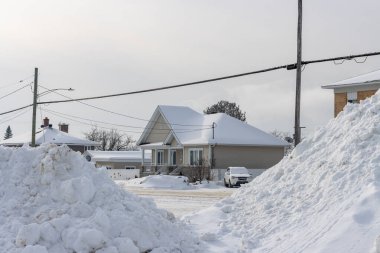 Kanada, 25 Ocak 2026: Karlı banliyö sokağı, yığınla kar, kışlık evler, bulutlu gökyüzü