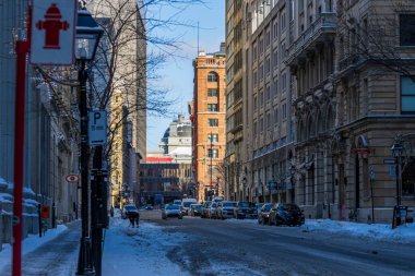 Kanada, Montreal, 24 Aralık 2025: Karlı şehir sokağı, park edilmiş arabalar, kış günü, kentsel mimari sahnesi.