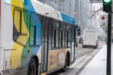 Kanada, Montreal, 23 Aralık 2025: Karlı şehir sokağı, halk otobüsü, dur işareti, yeşil ışık.