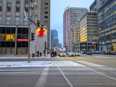Kanada, Montreal, 22 Aralık 2025: Kar, trafik, yayalar, yüksek binalar ile şehir caddesi kavşağı