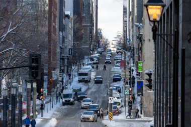 Kanada, Montreal, 24 Aralık 2025: Karla kaplı kentsel cadde, hareketli şehir hayatı, trafik, yayalar, kış günü.