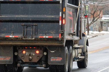 Kanada, Quebec, 27 Kasım 2025: Islak yolda çamurlu ve ışıklı büyük bir çöp kamyonu
