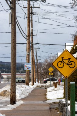 Kanada, Quebec, 27 Kasım 2025: Bisiklet levhası, elektrik hatları ve çocuk imzalı karlı kaldırım