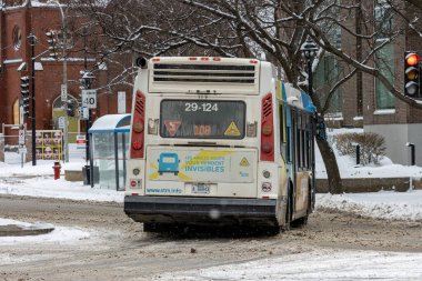 MONTREAL, CANADA, 25 Aralık 2025: Karlı şehir sahnesinde otobüs, trafik ışığı, reklam, karlı yol, binalar, ağaçlar