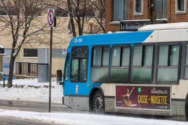 Kanada, Montreal, 25 Aralık 2025: Karlı şehirde mavi otobüs, yaya geçidi işareti yok.