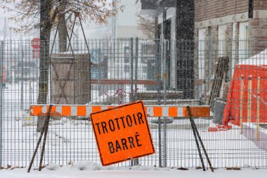Kanada, Quebec, 30 Kasım 2025: Karlı inşaat sahası kaldırımı turuncu tabela kış uyarısı