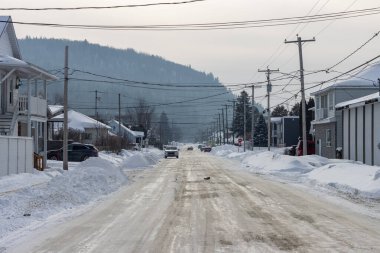 Kanada, 25 Ocak 2026: Karlı cadde, bulutlu gökyüzü, elektrik direkleri, kış manzarası, sakin mahalle, uzak tepeler