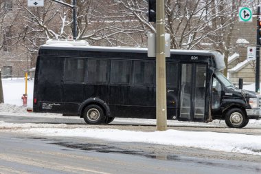 Kanada, Montreal, 25 Aralık 2025: Karlı caddede kışın trafik işaretleri yakınında siyah otobüs