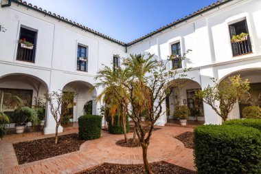 Huelva, İspanya 10.8.2025 Palos de la Frontera, İspanya 'daki La Rabida Manastırı iç avlusu, beyaz kemerler, Endülüs mimarisi, fayanslı döşemeler ve yemyeşil Akdeniz bahçesi.