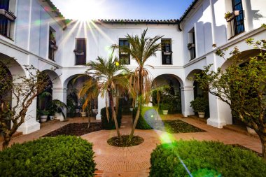 Huelva, İspanya 10.8.2025 Palos de la Frontera, İspanya 'daki La Rabida Manastırı iç avlusu, beyaz kemerler, Endülüs mimarisi, fayanslı döşemeler ve yemyeşil Akdeniz bahçesi.