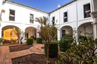 Huelva, İspanya 10.8.2025 Palos de la Frontera, İspanya 'daki La Rabida Manastırı iç avlusu, beyaz kemerler, Endülüs mimarisi, fayanslı döşemeler ve yemyeşil Akdeniz bahçesi.