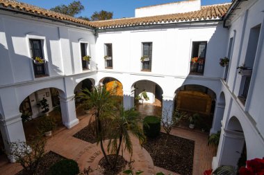 Huelva, İspanya 10.8.2025 Palos de la Frontera, İspanya 'daki La Rabida Manastırı iç avlusu, beyaz kemerler, Endülüs mimarisi, fayanslı döşemeler ve yemyeşil Akdeniz bahçesi.