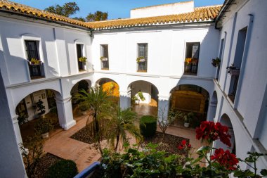 Huelva, İspanya 10.8.2025 Palos de la Frontera, İspanya 'daki La Rabida Manastırı iç avlusu, beyaz kemerler, Endülüs mimarisi, fayanslı döşemeler ve yemyeşil Akdeniz bahçesi.