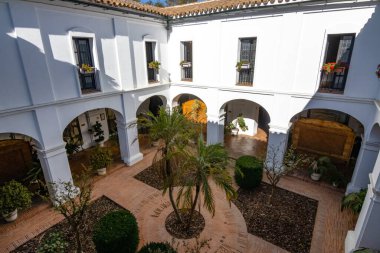 Huelva, İspanya 10.8.2025 Palos de la Frontera, İspanya 'daki La Rabida Manastırı iç avlusu, beyaz kemerler, Endülüs mimarisi, fayanslı döşemeler ve yemyeşil Akdeniz bahçesi.