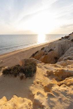 Günbatımında el değmemiş Arenosillo plajının yüksek açılı manzarası, Mazagon, Huelva, İspanya 'daki dramatik kumtaşı kayalıkları ve Atlantik kıyı şeridi.