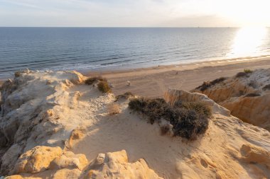 Günbatımında el değmemiş Arenosillo plajının yüksek açılı manzarası, Mazagon, Huelva, İspanya 'daki dramatik kumtaşı kayalıkları ve Atlantik kıyı şeridi.